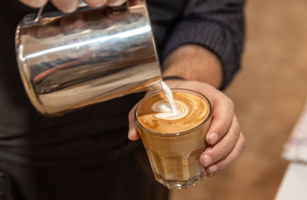 Una café con leche mientras se mezcla la leche y el café